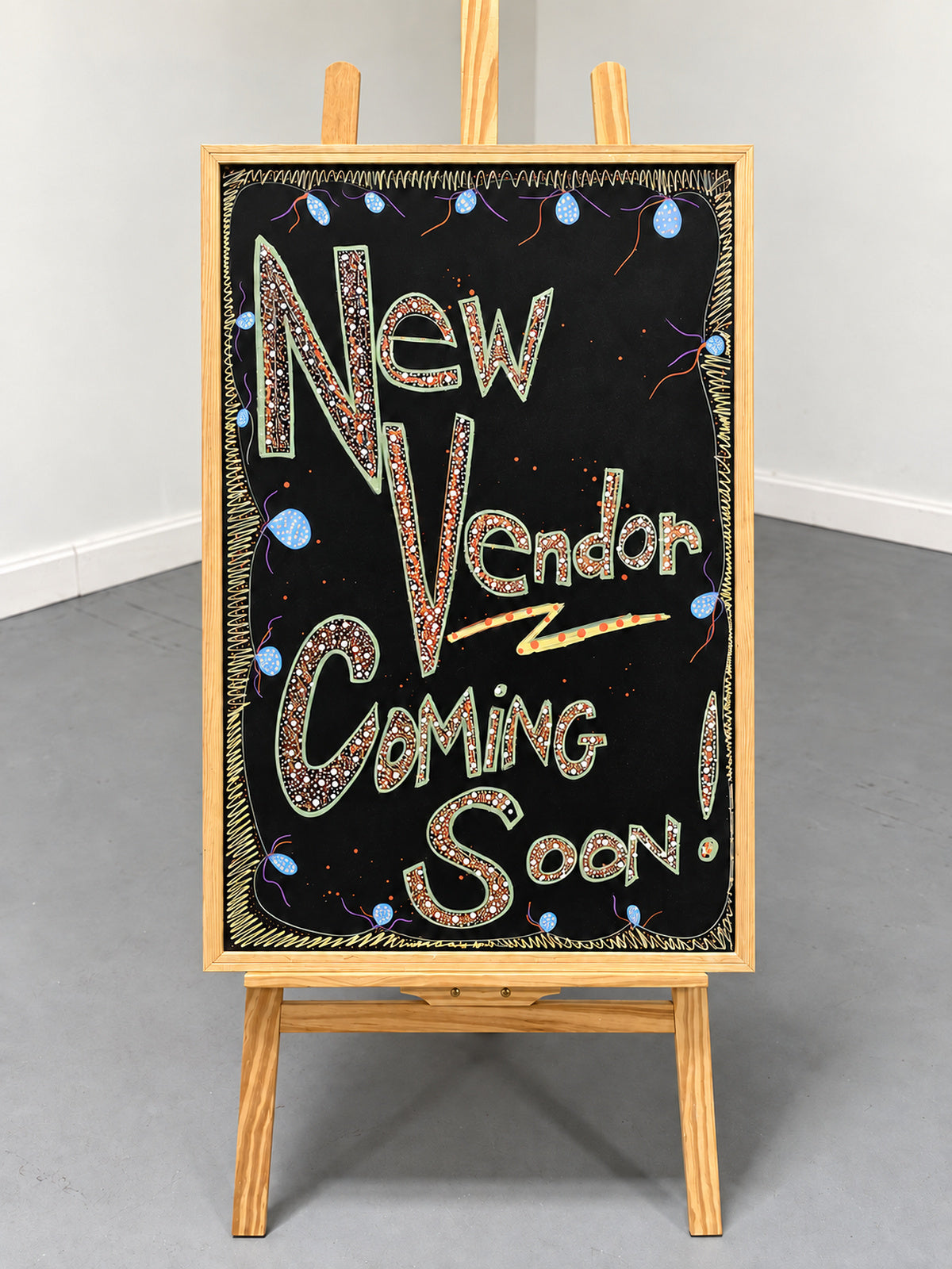 A chalkboard sign on a wooden easel reading New Vendor Coming Soon, in the Mississippi Antique Galleria.